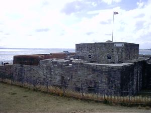 A gray, squat stone castle by the sea shore